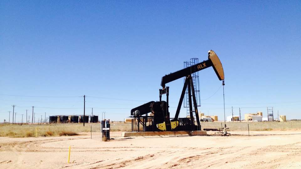 Oil pumpjack operating in a dry, sunny desert landscape, symbolizing oil and gas extraction.