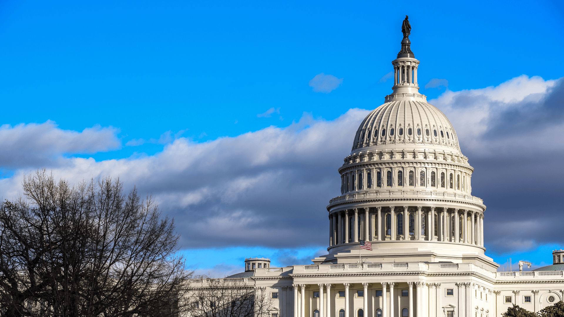 Exterior view of the U.S. Capitol Building dome and the Statue of Freedom against a dramatic blue sky with dark clouds.