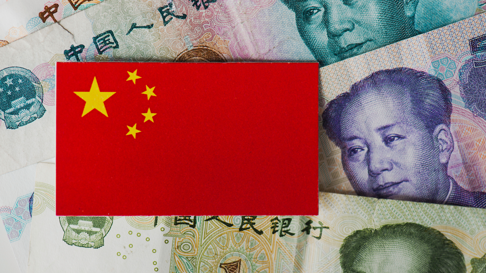 Chinese flag on top of yuan banknotes symbolizing US’s economy and currency.