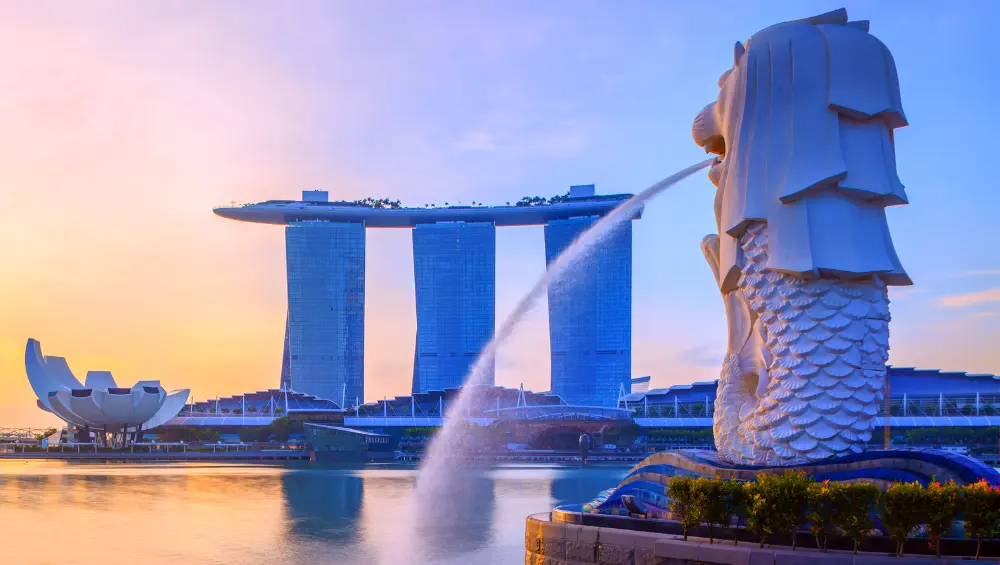 Merlion statue with Marina Bay Sands skyline at sunrise in Singapore.